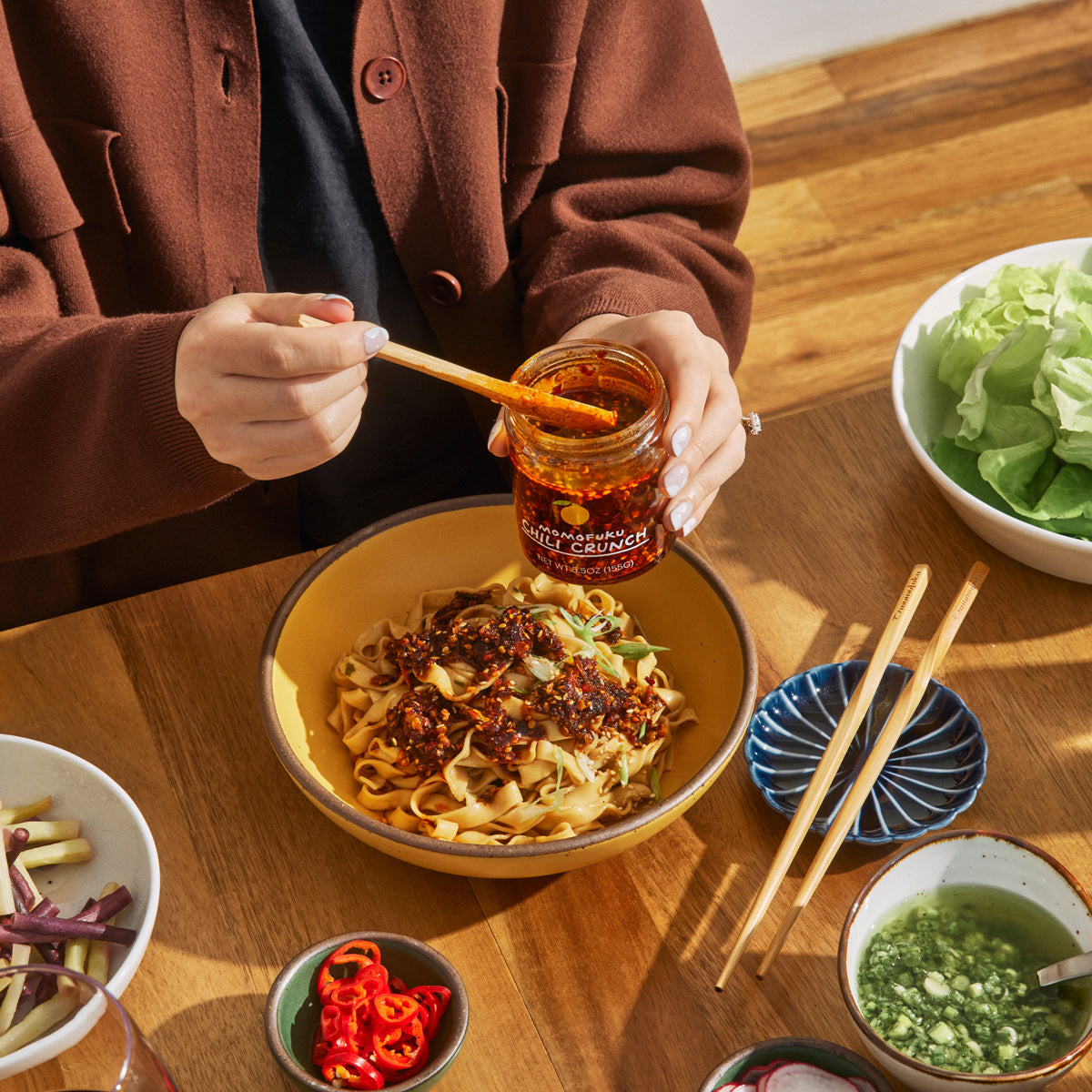 Chili crunch being spooned onto noodles