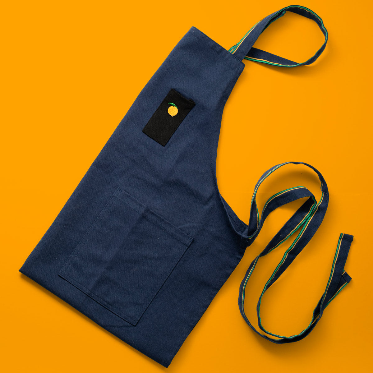 Folded Momofuku Apron on Orange Background