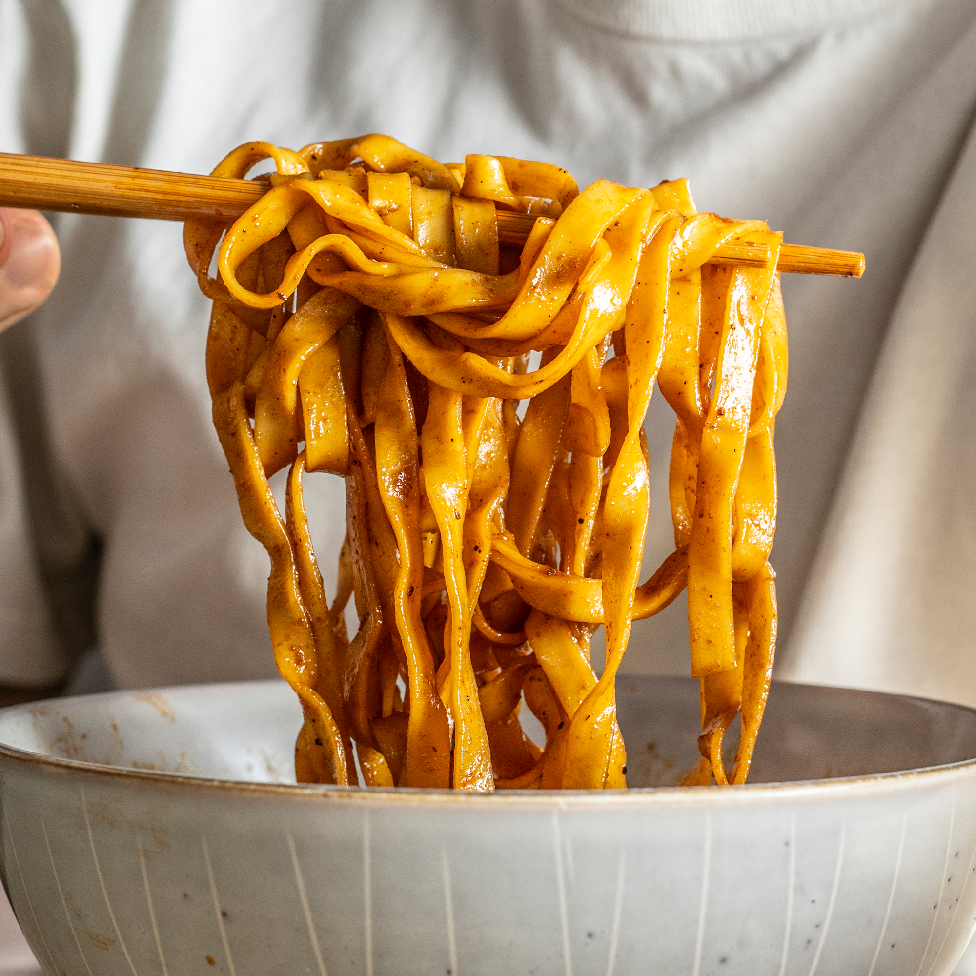 Noodles on chopsticks pulled from a bowl